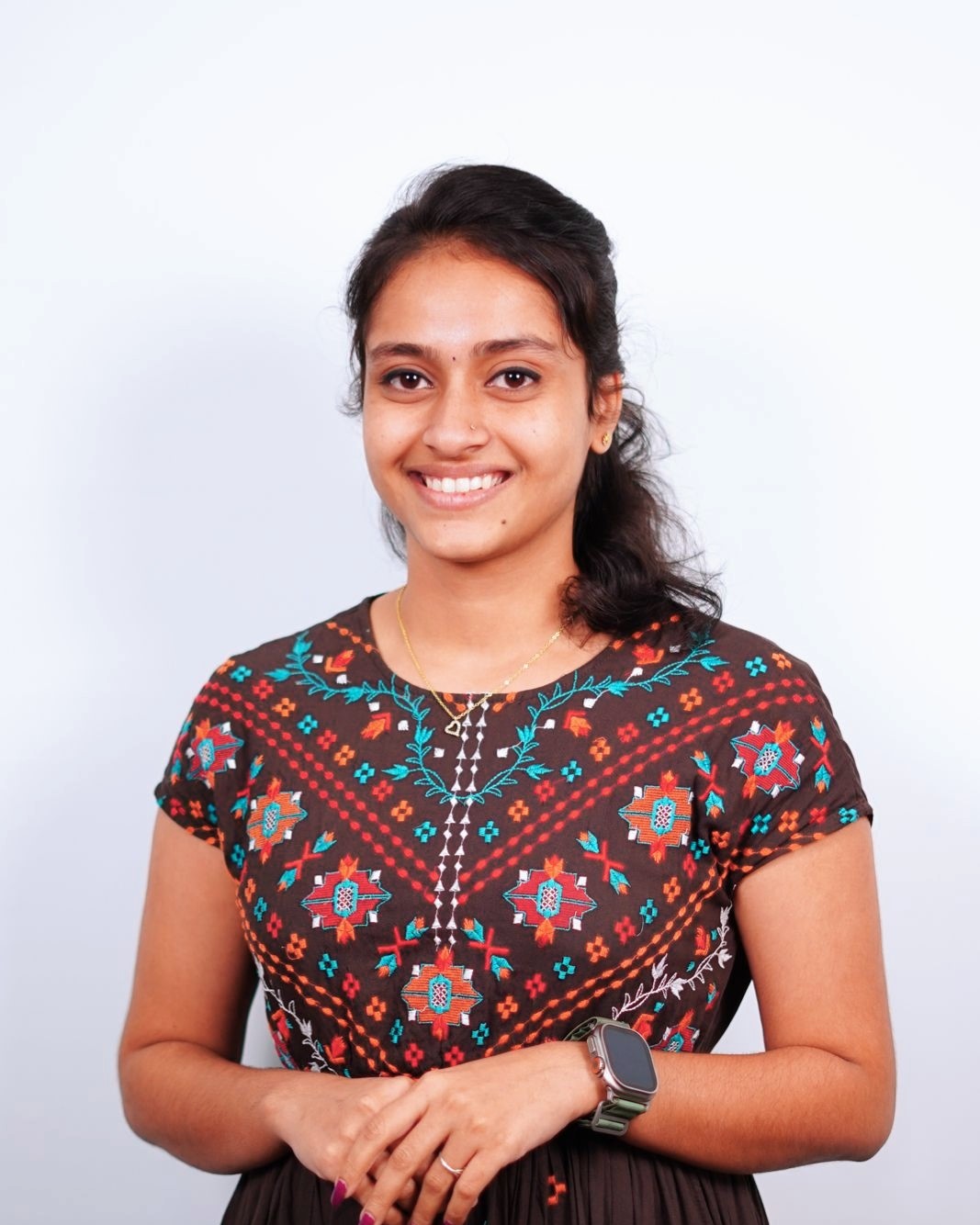 Portrait of a professional software developer in Kochi, Kerala, wearing a
						stylish brown dress with colorful embroidery, smiling confidently against a plain white
						background