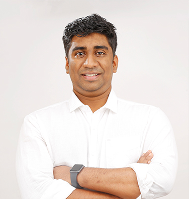 Confident software developer in Kochi, Kerala, dressed in a formal
						white shirt, standing against a clean white background with arms crossed.