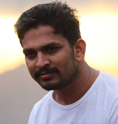 Portrait of a software developer in Kochi, Kerala, wearing a casual
						white t-shirt, captured with a scenic sunset in the background, showcasing a thoughtful
						demeanor.