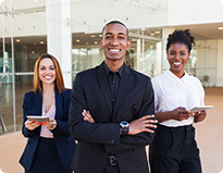 Three business professionals standing confidently in front of a modern office building, engaged in discussion.