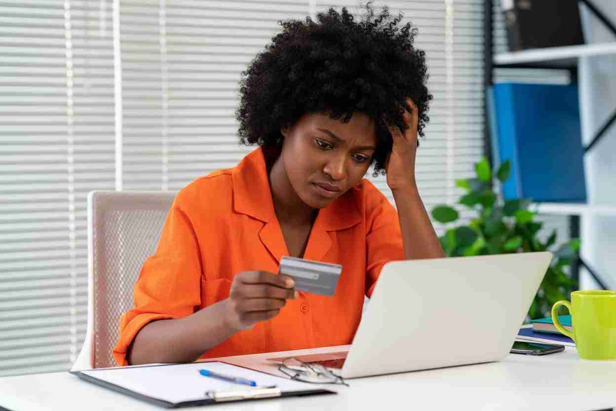 Frustrated woman with credit card at laptop